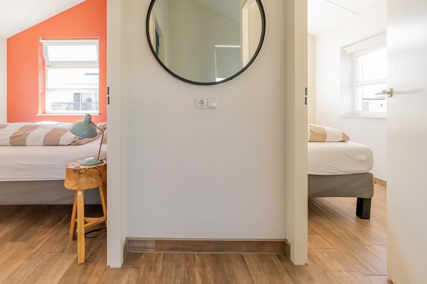 Une chambre à coucher avec un lit, une table de chevet, une lampe et un miroir rond accroché au mur.