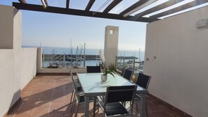 A terrace with a table and chairs, overlooking a marina with boats.