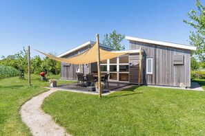Une maison moderne dotée d’un patio, d’une grande fenêtre et d’une porte.
