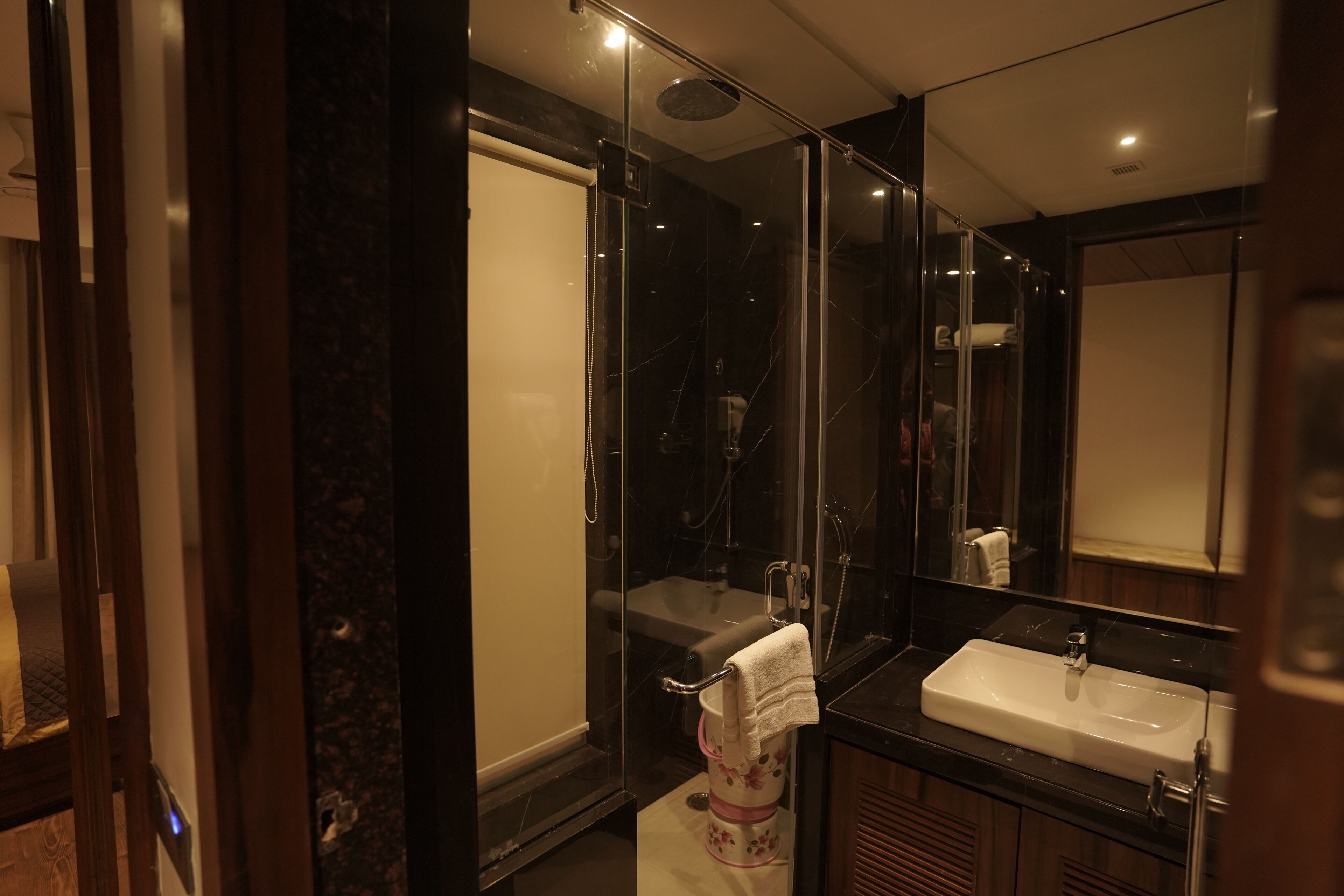 Un bany modern amb dutxa de vidre, un lavabo blanc i un mirall gran.