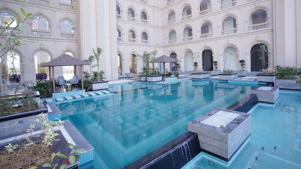 Una amplia piscina interior con varios niveles de balcones, rodeada de zonas de estar y jardineras.