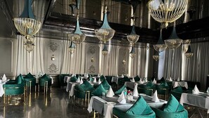 Un comedor formal con sillas tapizadas en verde, manteles blancos y detalles dorados.