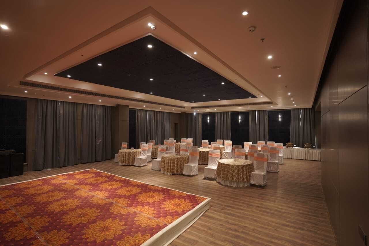 Ein geräumiger Saal mit hoher Decke, angeordneten Sitzplätzen und einem großen, gemusterten Teppich.