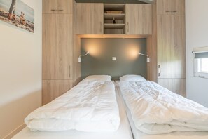 Une chambre double avec deux lits, une armoire en bois et un tableau au mur.