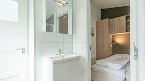 Une salle de bain moderne avec un lavabo blanc, un miroir et des meubles en bois.