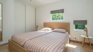 Un dormitorio con cama, lámparas de noche, una ventana y vistas a zonas verdes.
