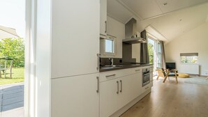 Una cocina moderna con armarios blancos, horno integrado y un ventanal amplio.