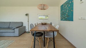 Un comedor con una mesa de madera, sillas, una lámpara de pie, un sofá y un cuadro en la pared.