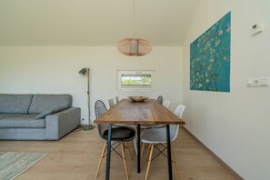 Un comedor con una mesa de madera, sillas, una lámpara de pie, un sofá y un cuadro en la pared.