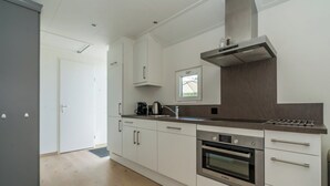 Una cocina moderna con armarios blancos, un horno Bosch, una campana extractora de acero inoxidable y una ventana sobre el fregadero.