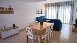 A modern living room with a dining area, a blue sofa, and a small table with chairs.
