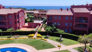 Ein Wohnkomplex mit mehreren Mehrfamilienhäusern, einem Schwimmbad und Blick auf das Meer.