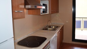 A kitchen with wooden cabinets, a stainless steel sink, and a built-in microwave.