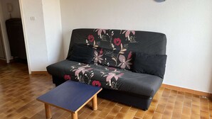 A living room with a sofa and a small wooden table. - Charming Studio with Pool, Balcony, and Central Location for 2 in Agde (Cap d'Agde)