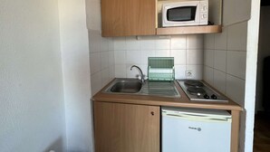 A compact kitchen with a microwave, sink, and dishwasher. - Charming Studio with Pool, Balcony, and Central Location for 2 in Agde (Cap d'Agde)