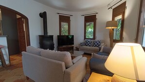 A living room with a sofa, a television, a fireplace, and a lamp. - Charming Rustic Villa with Pool & Mediterranean Garden (L'Ametlla de Mar)