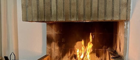 A fireplace with a brick surround and a wooden mantel.