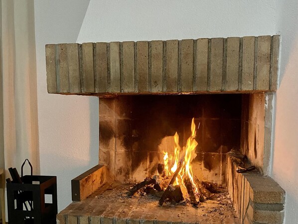 A fireplace with a brick surround and a wooden mantel.
