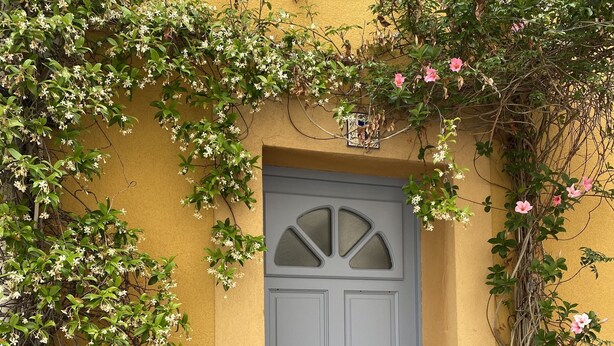 Un bâtiment jaune avec une porte grise et un petit marchepied menant à l’entrée.