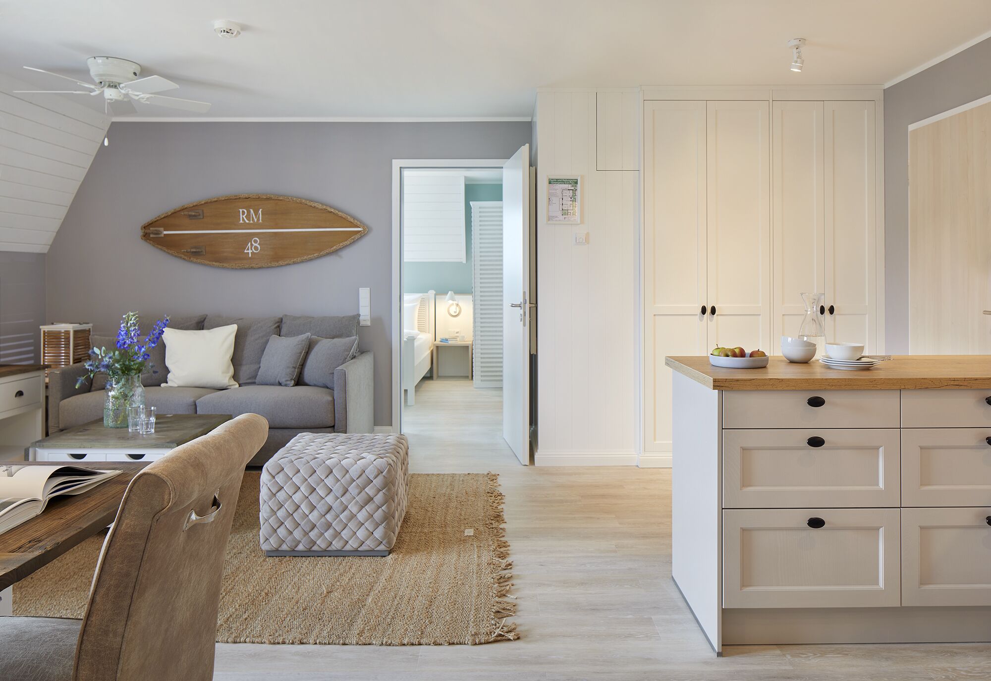 Una cocina moderna con armarios blancos, encimera de madera y comedor con mesa y sillas.