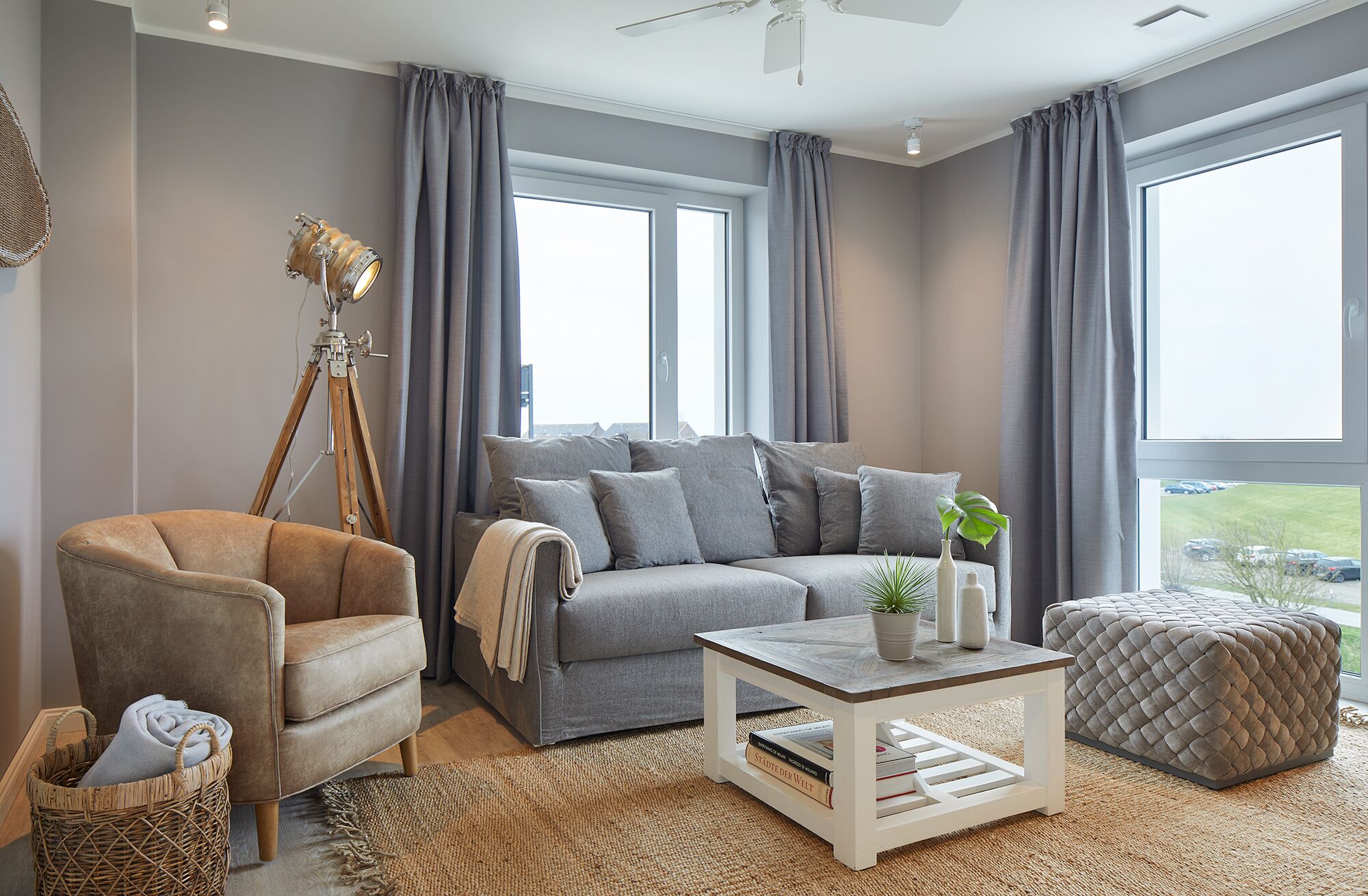 A living room with a sofa, armchair, coffee table, and a tripod lamp.