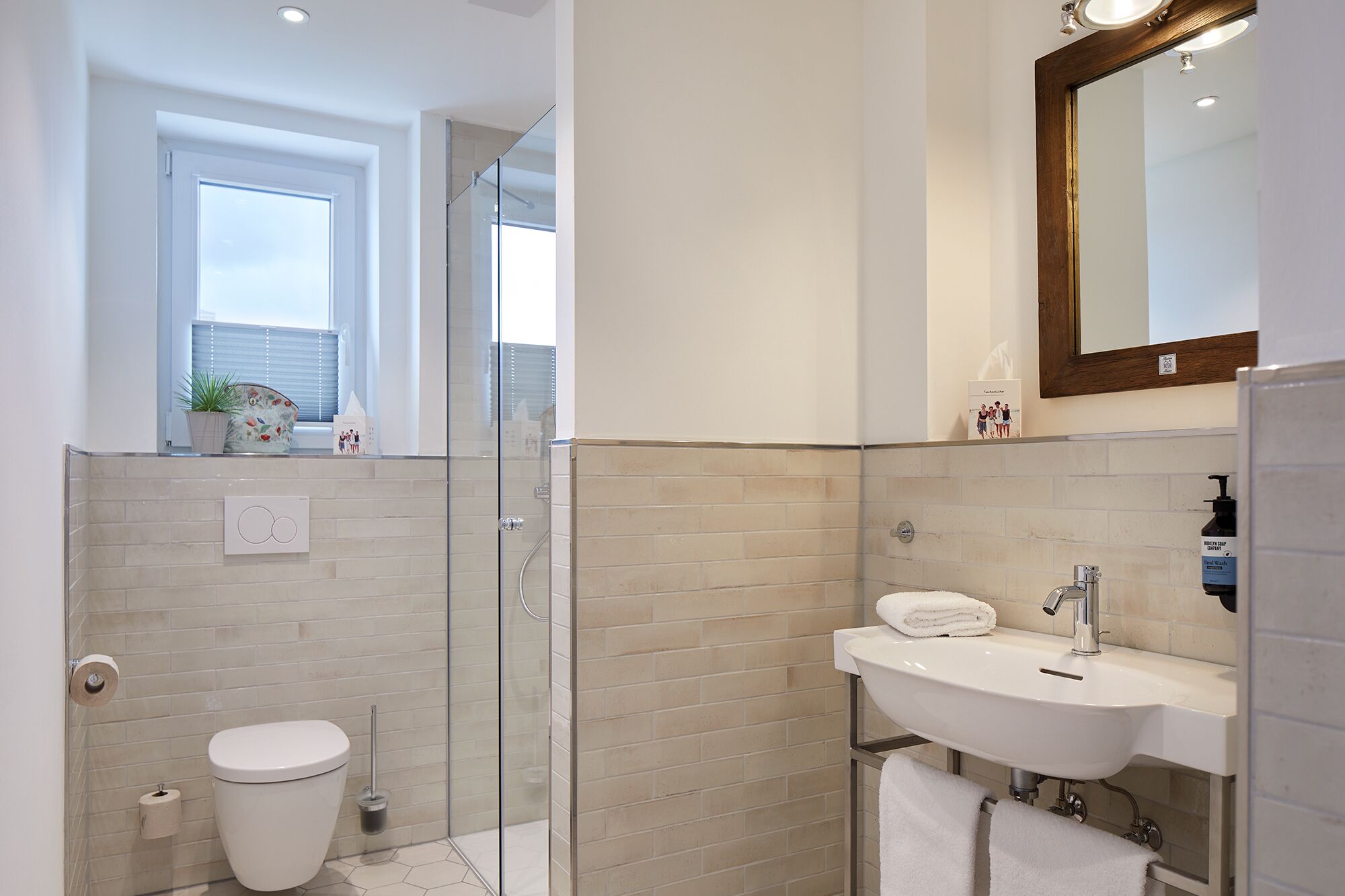 A modern bathroom with a glass-enclosed shower, a white sink, and a toilet.