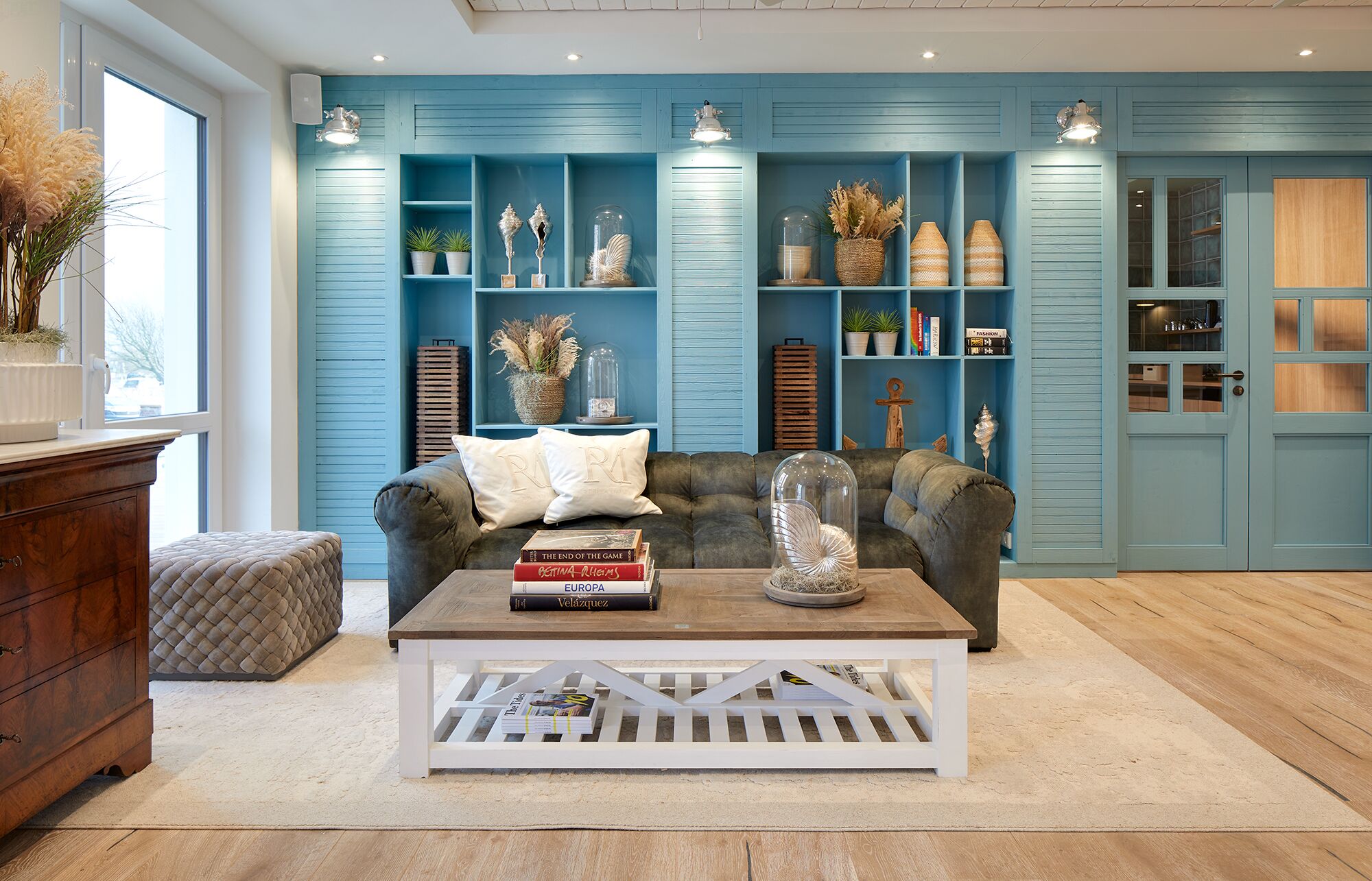 Un salon avec un mur bleu, un canapé marron, une table basse blanche et un meuble en bois.