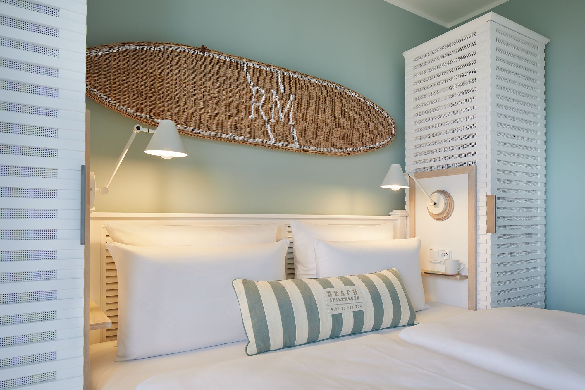 A bedroom with a bed, a wicker basket, and a wall-mounted shelf.