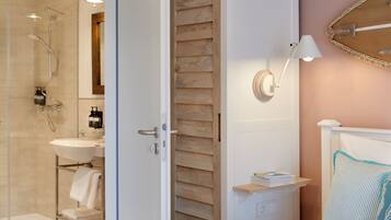 Un baño moderno con cabina de ducha de vidrio, un lavabo blanco y un panel de pared de madera.