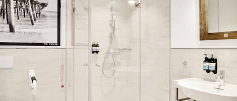 Une salle de bain moderne avec une douche à parois de verre, un lavabo blanc et un grand miroir.