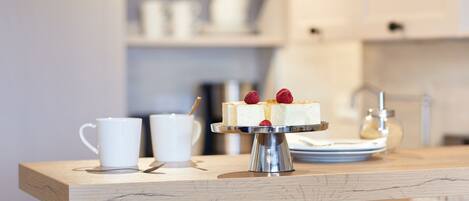 A dessert on a metal stand with a white cup and a spoon on a wooden table.