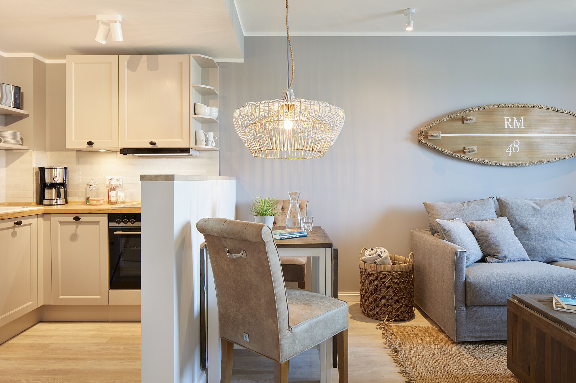 A modern kitchen with white cabinets, a coffee machine, and a hanging light fixture.