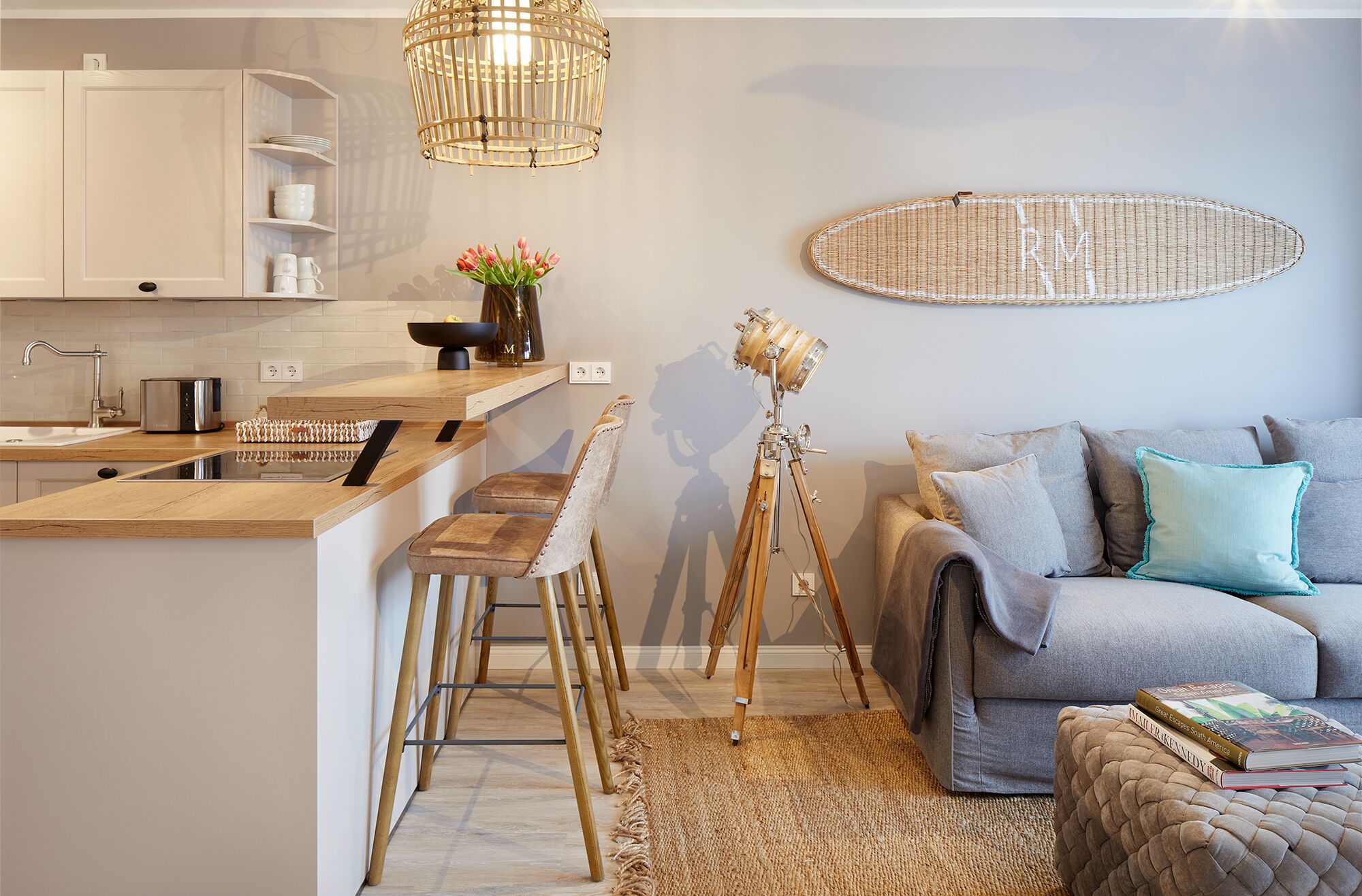 Une cuisine moderne avec un plan de travail en bois, des tabourets de bar et un luminaire suspendu.