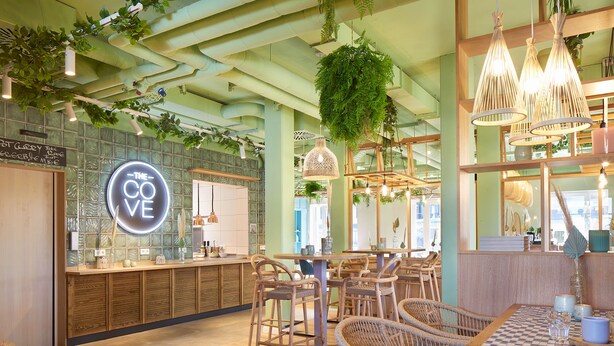A restaurant interior with wicker furniture, hanging plants, and pendant lighting. - Beach Apartments Büsum (Büsum)