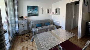 Un espace de vie compact comprenant un canapé, une table à manger et un coin cuisine.