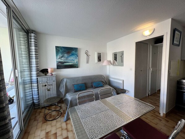 Ett kompakt bostadsutrymme med en soffa, ett matbord och ett köksområde.