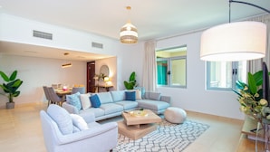 Una sala de estar moderna con un sofá modular, una mesa de centro y un comedor con sillas y una mesa.