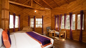 A wooden cabin bedroom with a bed, desk, and chair.