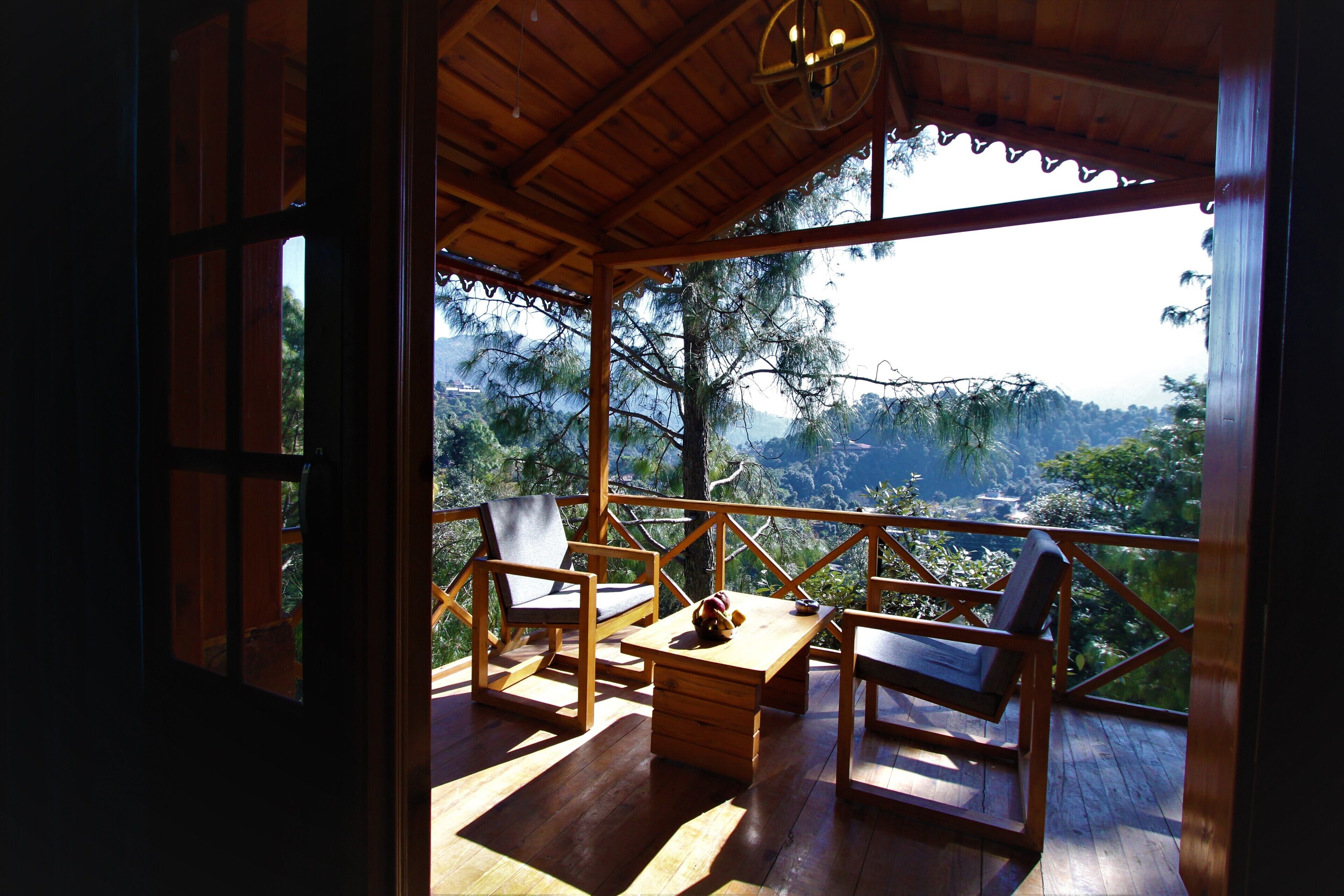 A wooden deck with a table and chairs, overlooking a mountainous landscape.