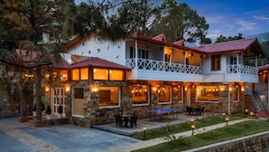 A two-story building with a balcony, stone walls, and outdoor seating.