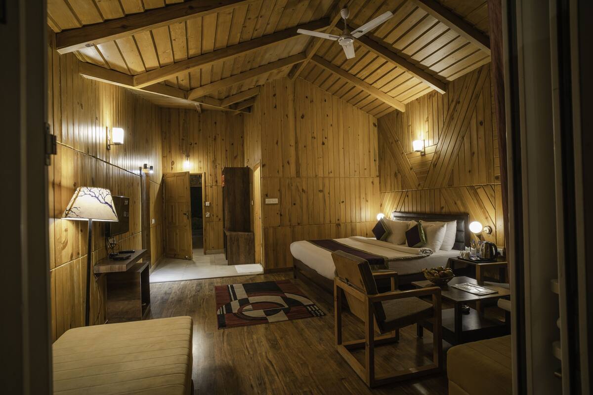 Una habitación acogedora de madera con una cama, un escritorio, una silla y un ventilador de techo.