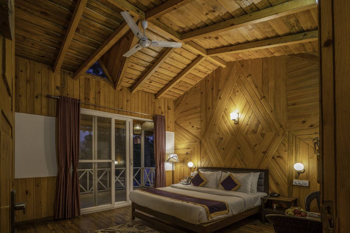 Un dormitorio de cabaña de madera con cama, mesitas de noche y ventilador de techo.
