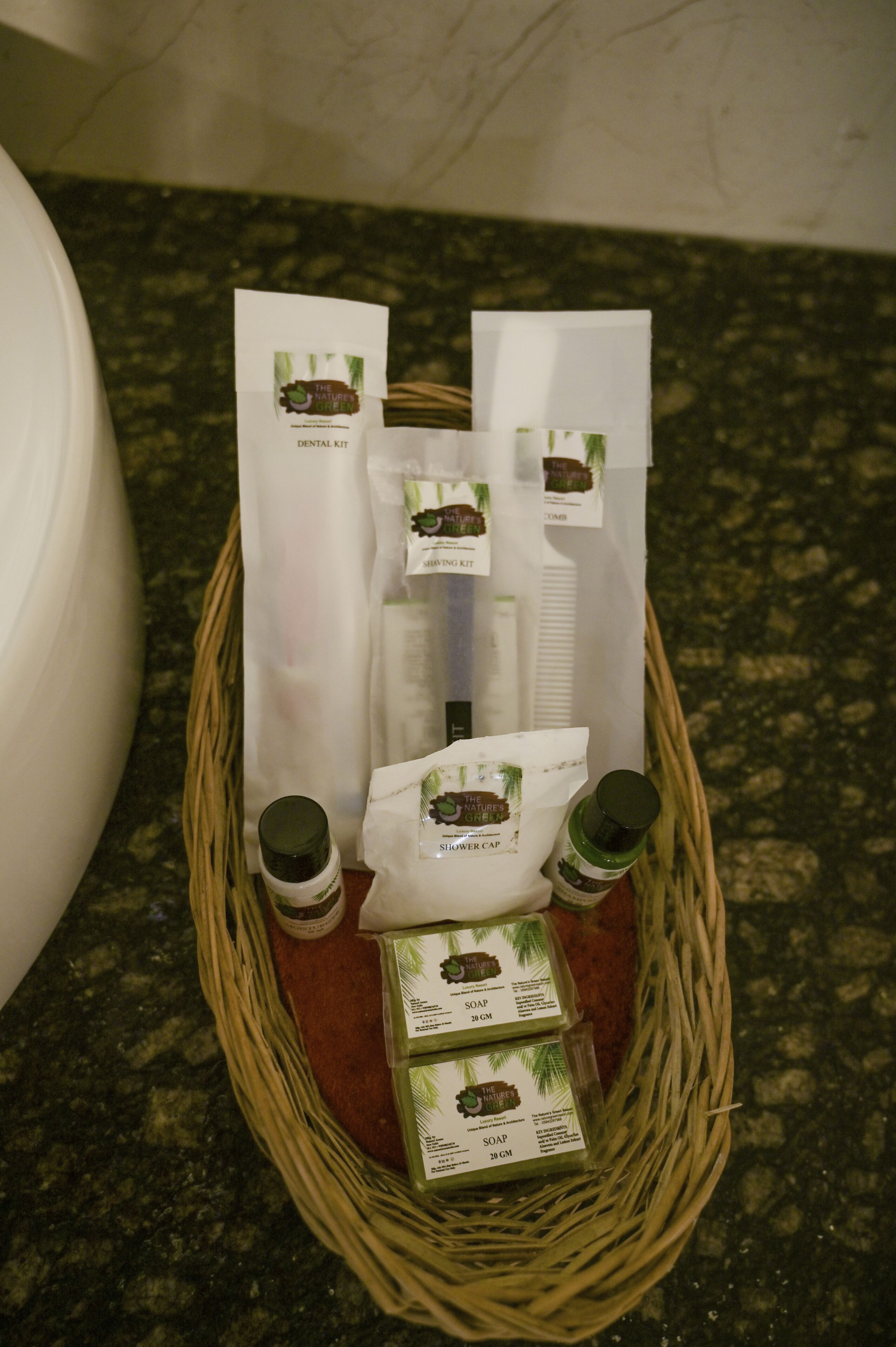 A wicker basket containing a dental kit, a shower cap, and two bottles of soap.