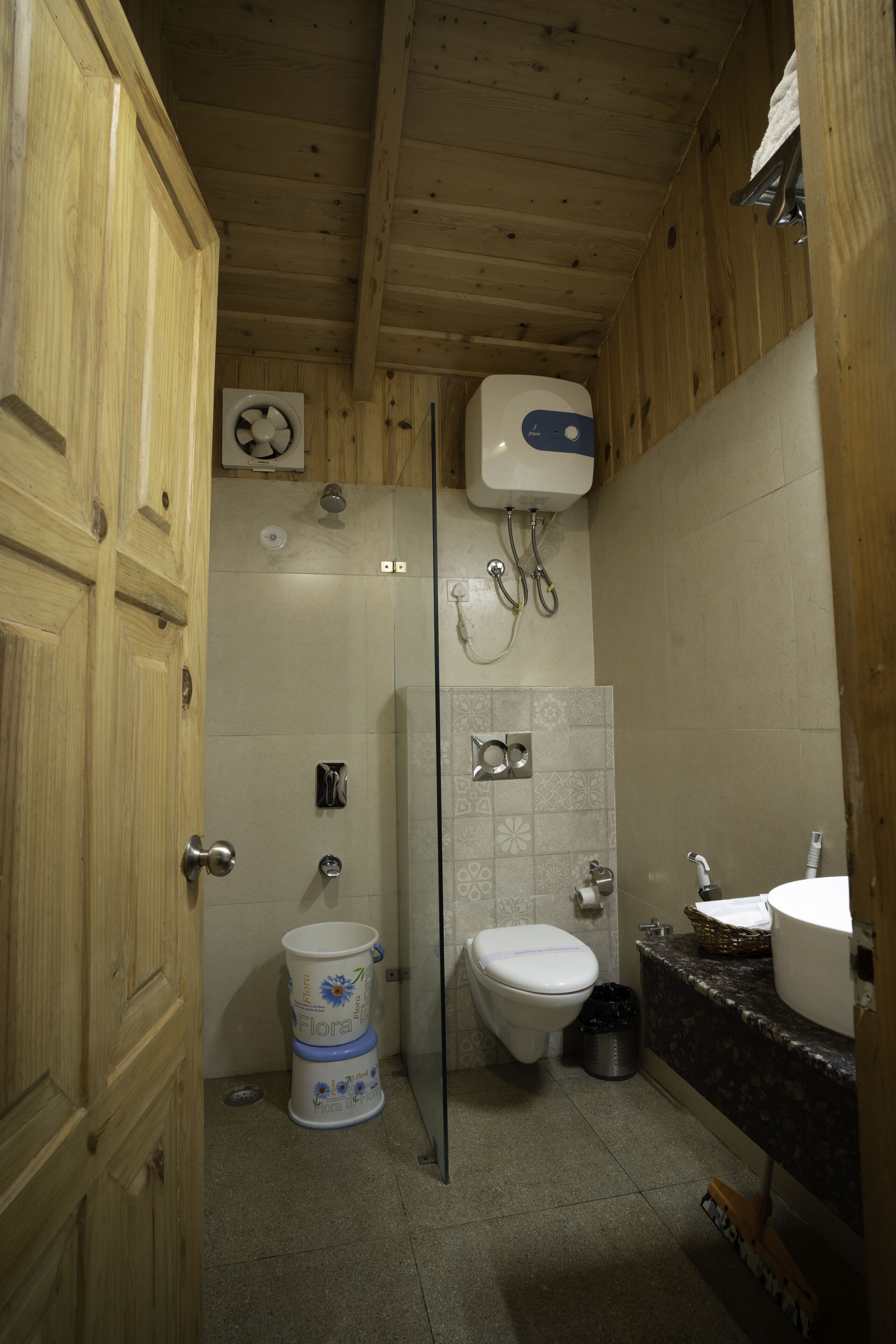 A wooden cabin bathroom with a toilet, shower, and sink.