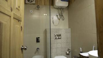 A wooden cabin bathroom with a toilet, shower, and sink.
