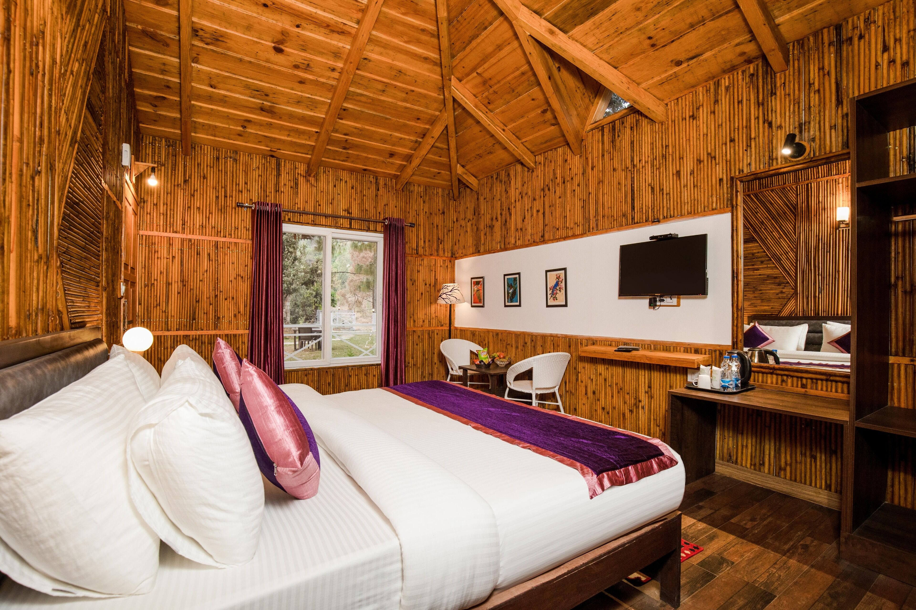 A wooden-paneled room with a bed, a desk, and a TV.