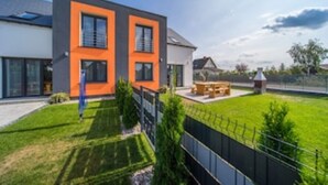 Una casa moderna de dos plantas con un césped cuidado y un área de patio.
