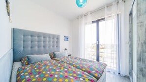 Un dormitorio con una cama grande, un cabecero gris y una colcha de lunares coloridos.