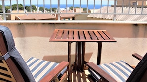 A balcony with a wooden table and two striped cushioned chairs. - Spacious Duplex 300m from Beaches, Includes Parking (L'Ametlla de Mar)