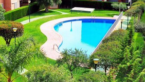 A swimming pool surrounded by well-maintained greenery and a building with balconies. - Spacious Duplex 300m from Beaches, Includes Parking (L'Ametlla de Mar)